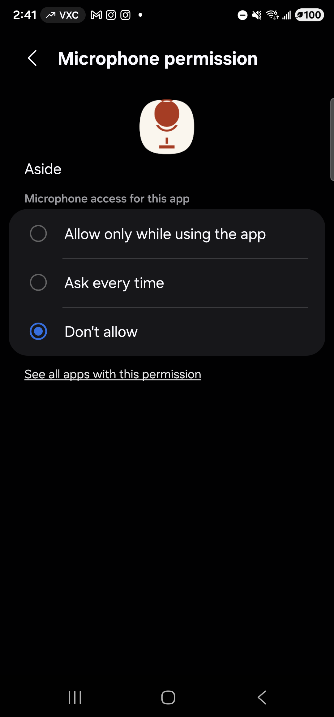 The Samsung One UI Microphone permission detail screen for Aside, in dark mode. Header reads ‘Microphone permission’ with a back arrow on the left. Centered near the top: the warm-paper Aside icon (clay mic glyph), then the app name ‘Aside’ left-aligned beneath it. Below ‘Aside’, the small gray label ‘Microphone access for this app’. Below that, a single rounded card containing three radio-button rows separated by hairline dividers: ‘Allow only while using the app’ (empty radio) — highlighted as the next tap target — ‘Ask every time’ (empty radio), and ‘Don’t allow’ with its radio currently selected (a filled blue circle inside a blue ring). Below the card, a single underlined link reads ‘See all apps with this permission’. The rest of the screen is empty black.