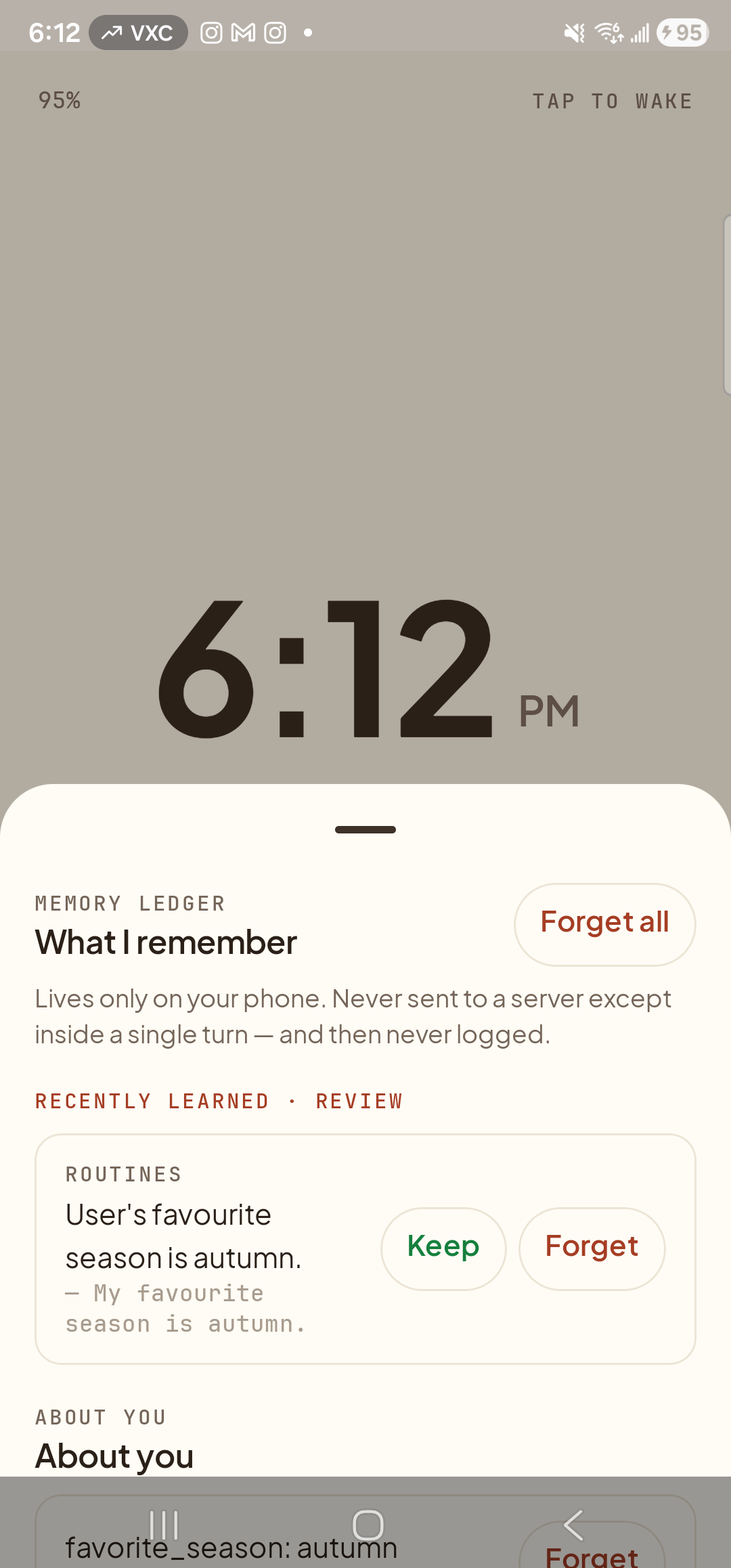 The Memory tab open as a bottom sheet over Aside’s dimmed ambient clock view. At the top of the sheet, the eyebrow ‘MEMORY LEDGER’ sits above the heading ‘What I remember’ with a clay-red ‘Forget all’ pill on the right of the header row. Below the header, a footnote reads ‘Lives only on your phone. Never sent to a server except inside a single turn — and then never logged.’. Below that, a clay-red eyebrow ‘RECENTLY LEARNED · REVIEW’ marks a new section containing one candidate row: an eyebrow ‘ROUTINES’, the content ‘User’s favorite season is autumn.’ followed by the original utterance ‘— My favorite season is autumn.’, and on the right two buttons — a green outlined ‘Keep’ button and a clay-red outlined ‘Forget’ button. Below the review section the active ‘ABOUT YOU’ heading begins with the row ‘favorite_season: autumn’.