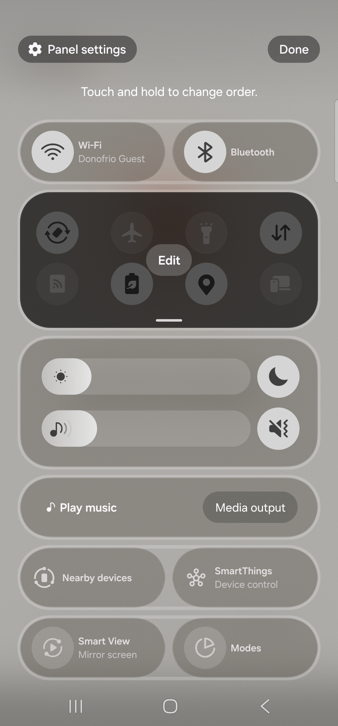 The Samsung One UI Quick Settings tray in edit mode. Header now shows ‘Panel settings’ at the top-left and a ‘Done’ pill button at the top-right, with the caption ‘Touch and hold to change order.’ above the active tray. The first row of tiles is Wi-Fi and Bluetooth; the second row sits inside a dark rounded panel with a small floating ‘Edit’ chip in the center and contains Auto rotate, Flight mode, Flashlight, Mobile data, Mobile Hotspot, Power saving, Location, Link to Windows. Below the active tray, the screen continues with brightness, media controls, and additional tile rows (Play music / Media output, Nearby devices / SmartThings, Smart View / Modes). The Aside tile is supposed to appear in the available-tiles area; if it isn’t visible yet, restart the phone — Samsung’s SystemUI caches the tile list aggressively on first install.